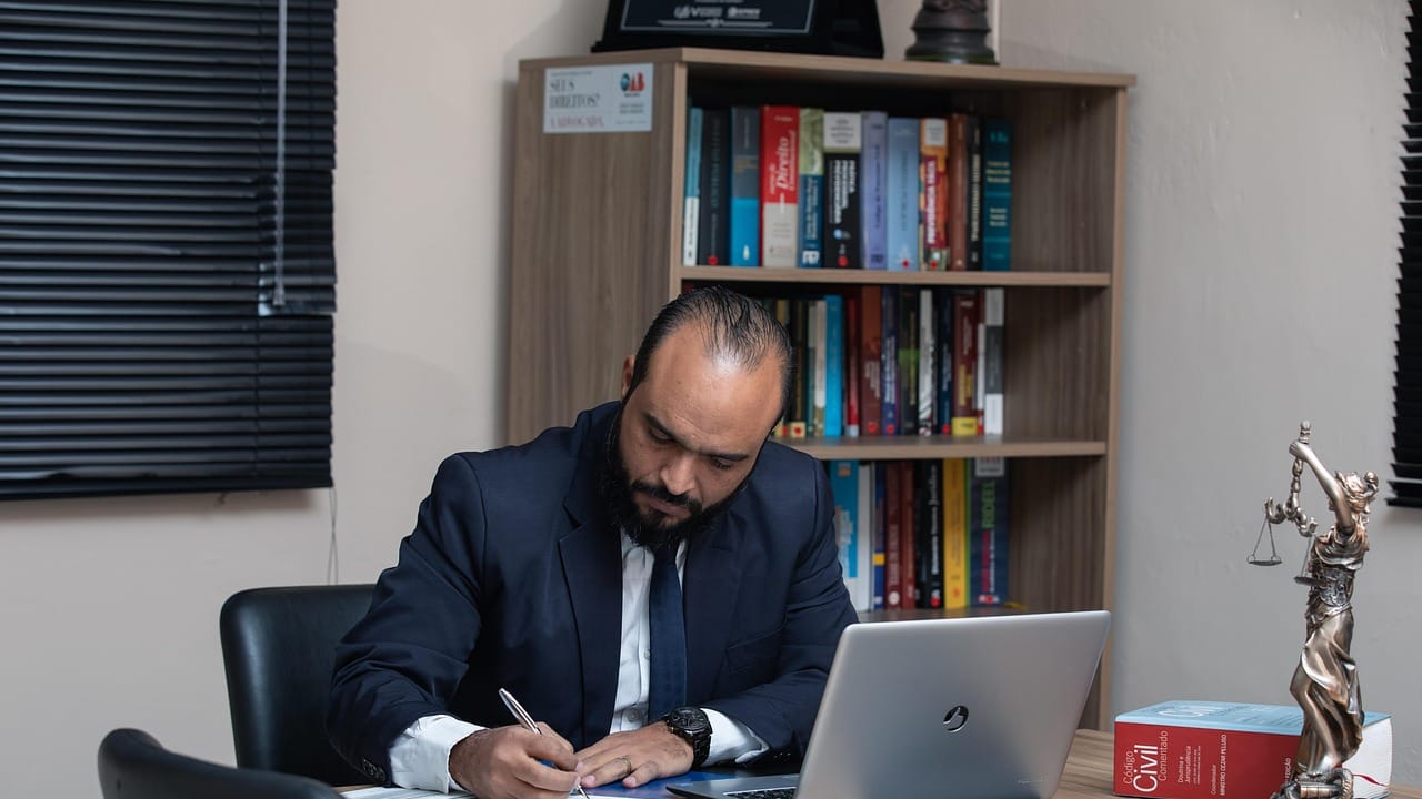An accountant working at his desk in an office lined with books